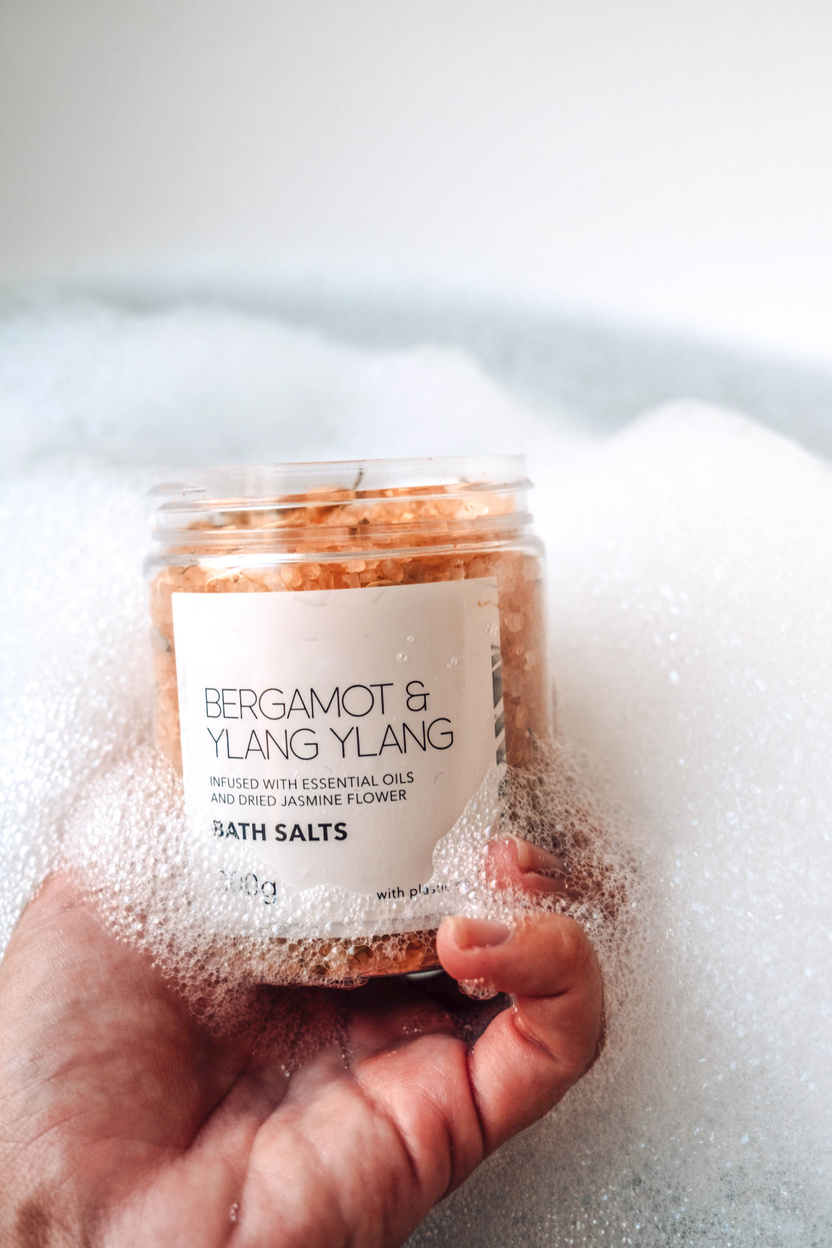 Person Holding a Jar of Bath Salts in the Tub